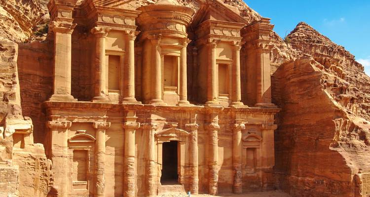 Close-up view of Petra’s imposing Monastery façade glowing under a bright blue sky.