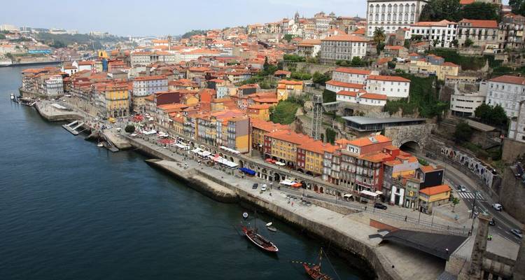 Oblique aerial of Porto’s colourful Ribeira riverside houses lining the Douro with boats and bridges below.