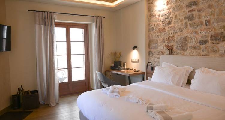 Cozy stone-accented hotel room with king bed, soft lighting and balcony doors.