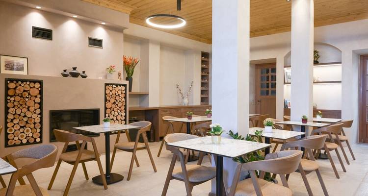 Bright, minimalist café interior with marble tables, wooden chairs and stacked firewood décor.
