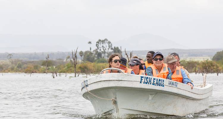 Open motorboat with tourists in life vests cruising on a lake with distant hills