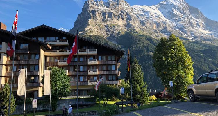 Hotel de resort de montaña con banderas nacionales colocadas bajo un majestuoso pico cubierto de nieve.