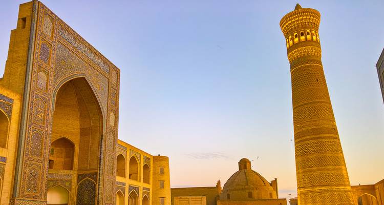 Golden evening light illuminates the towering Kalyan Minaret and arched madrasa walls in Bukhara.