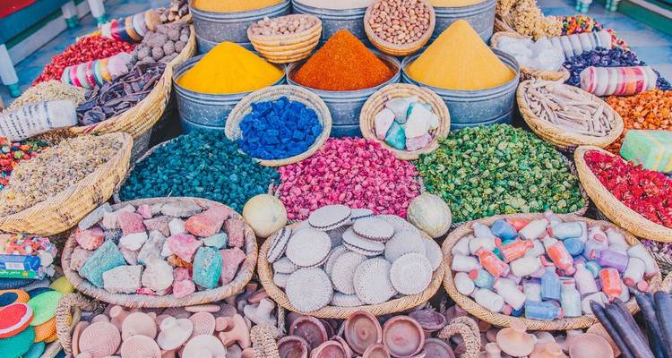 Les paniers débordent d'épices colorées, de pétales et d'herbes dans un étalage de marché marocain.