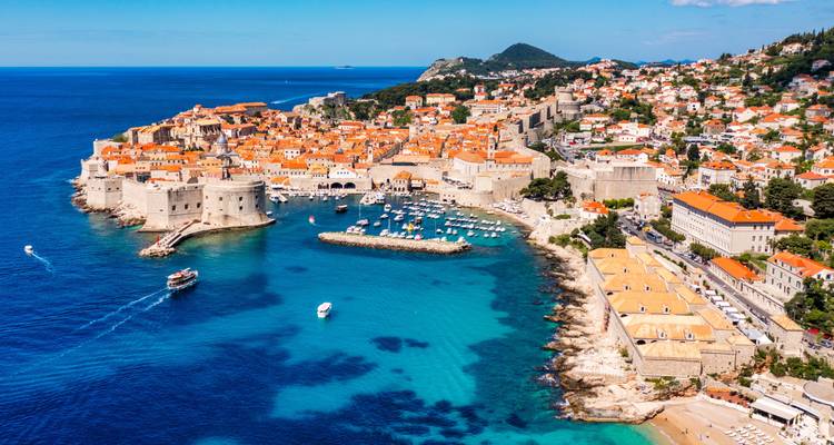 Spektakuläre Luftaufnahme der terrakottafarbenen Dächer der Altstadt von Dubrovnik, umgeben von türkisfarbenem Adriatischen Meer und Steinmauern.