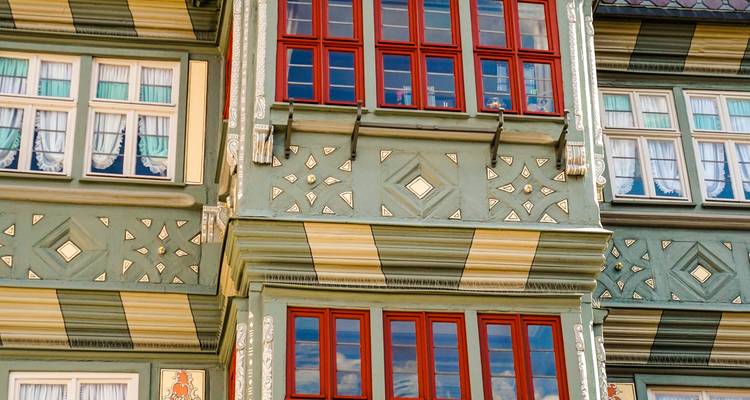 Close-up of ornate green and red timber-framed facade with decorative windows in a historic town