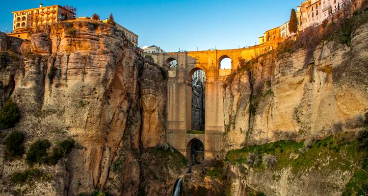 Dramatic stone bridge spanning a deep gorge at golden hour in Ronda.