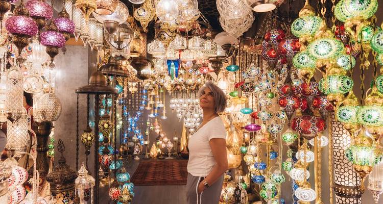 Mujer admirando filas de coloridas lámparas de mosaico turco en una tienda de bazar.