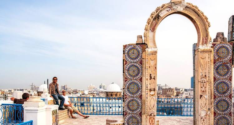 Rooftop terrace in Tunis medina with ornate archway and mosaic columns overlooking city