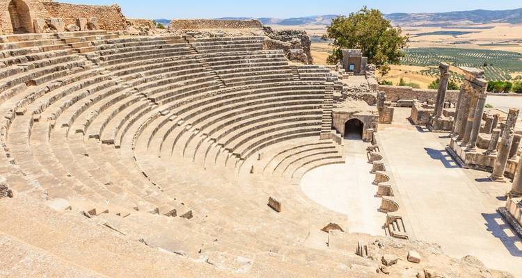 Well-preserved Roman amphitheatre set on a hill with sweeping stone seating and rural countryside in the background