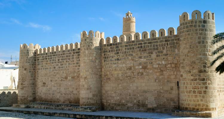 Los gruesos muros de arenisca almenados y una torre de vigilancia cilíndrica del histórico fuerte Ribat dominan una plaza vacía en Sousse.