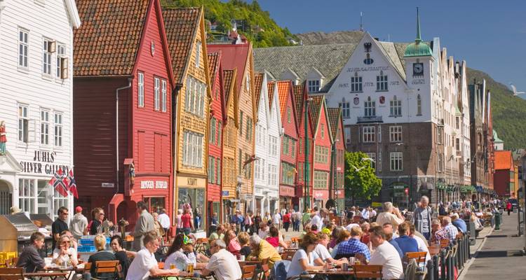 Les cafés extérieurs animés bordent les bâtiments hanséatiques aux bois colorés de Bryggen à Bergen par une journée ensoleillée.