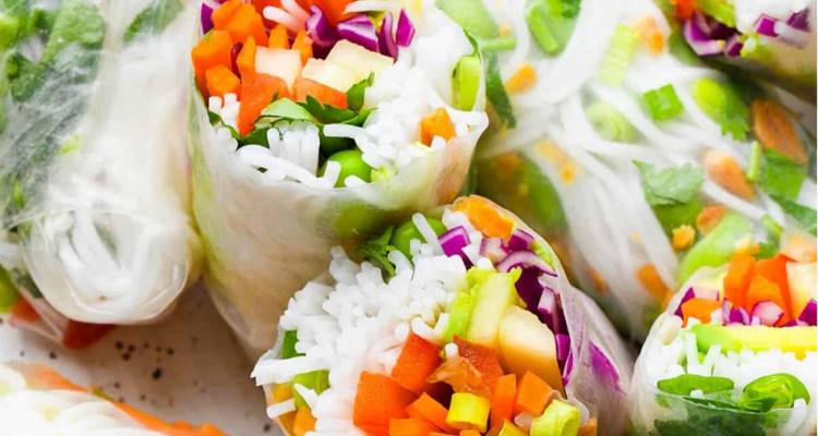 Gros plan de délicieux rouleaux de printemps vietnamiens garnis de légumes colorés, d'herbes aromatiques et de nouilles de riz.