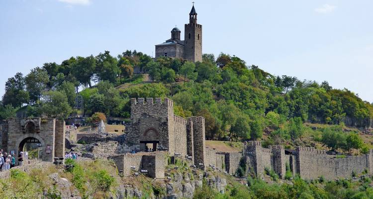 Ruins and walls of Tsarevets Fortress descending a rocky hillside toward visitors.