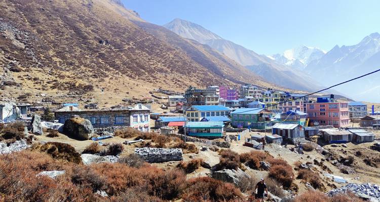 Village himalayen isolé avec des lodges colorés dispersés le long d'une vallée de montagne aride.