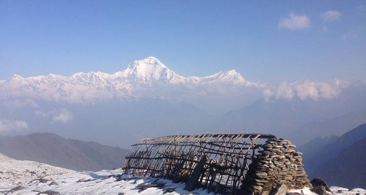 Champ de neige escarpé avec un abri en pierre délabré surplombant le Dhaulagiri lointain.