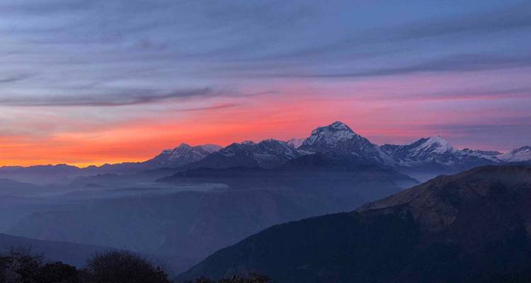 Alba magenta y naranja sobre capas de valles brumosos y el macizo de Annapurna.