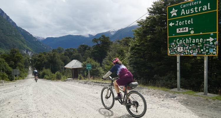 Rider on a gravel road passes a sign for Carretera Austral toward Tortel and Cochrane.