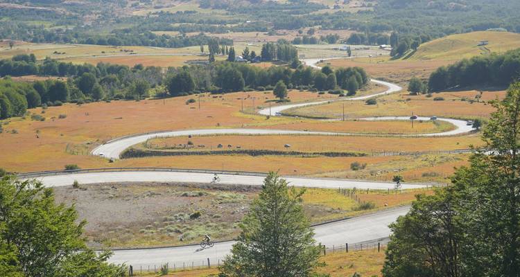 Bird’s-eye view of a winding ribbon road curving through rolling golden meadows.