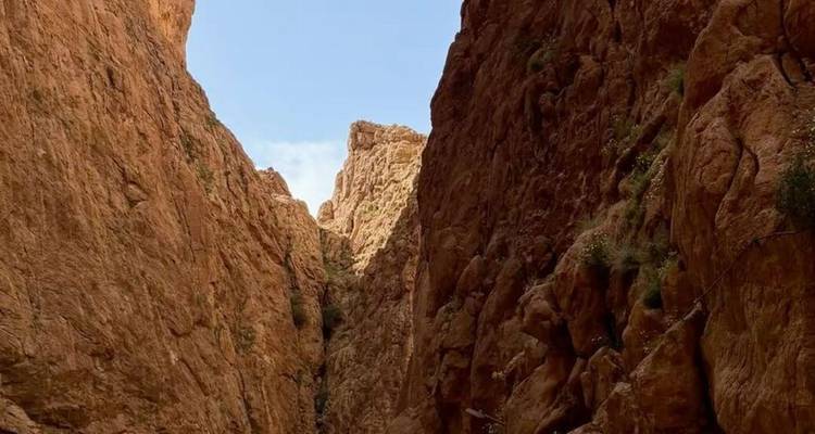 Gorge rocheuse étroite de couleur rougeâtre s'élevant abruptement vers une parcelle de ciel bleu.