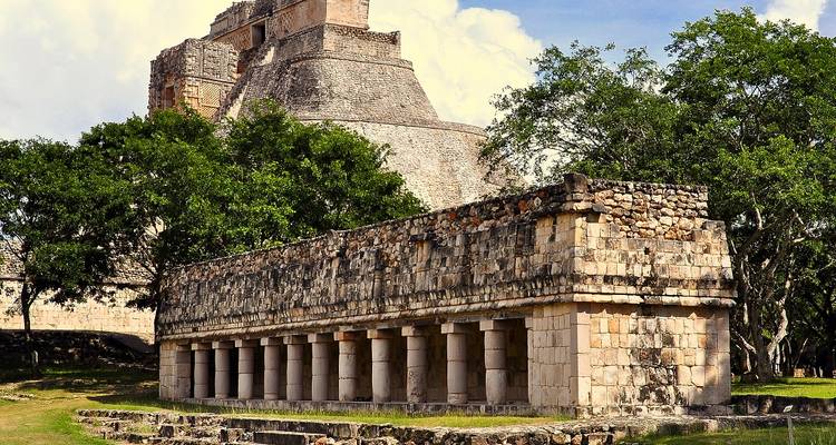 Ruins of Uxmal featuring ancient stone structures amid green trees under partly cloudy skies
