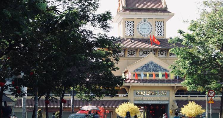 Front façade of Binh Tay Market clock tower decorated with national flags and colorful banners in Ho Chi Minh City