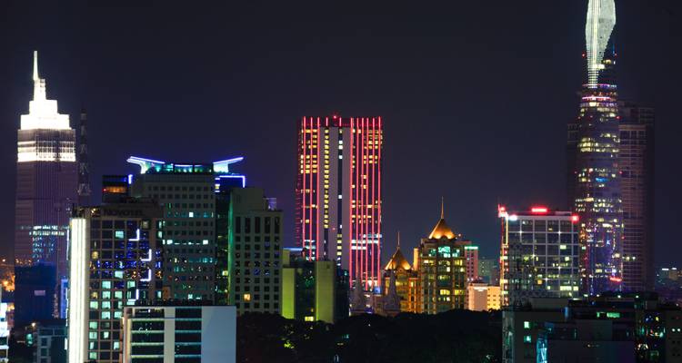 Colorful illuminated skyscrapers dominate Ho Chi Minh City’s night skyline against a dark sky