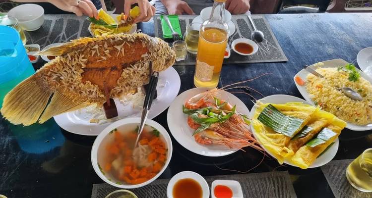 Traditionele Vietnamese maaltijd met hele gebakken vis, garnalen, rijst en drankjes op tafel.