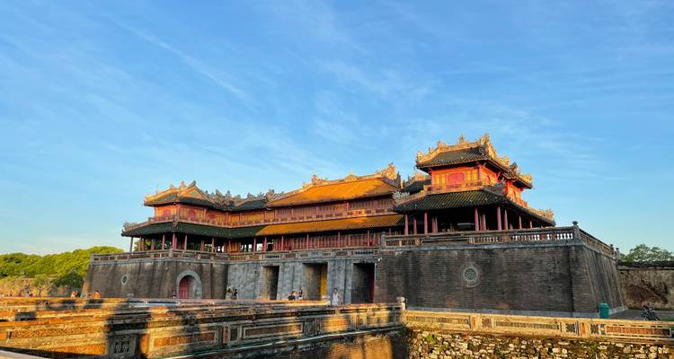 The ancient palace walls of Hue Citadel stand under a bright blue morning sky with warm sunlight on stone.