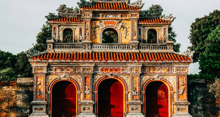 A richly decorated yellow and red gate of Hue’s Imperial enclosure stands against a soft morning sky.