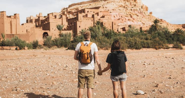 Young couple holding hands while facing the fortified village of Ait Benhaddou