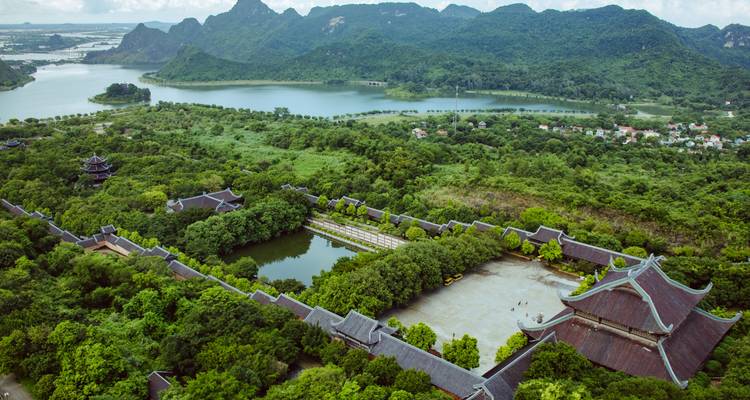 Aerial perspective of a vast temple complex surrounded by lush lakes and forested mountains.