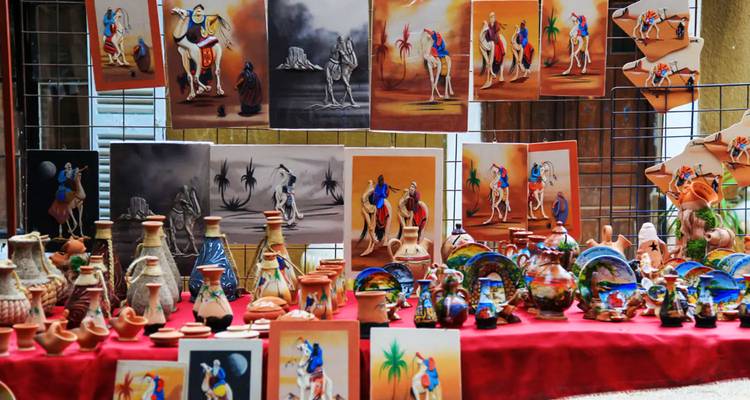 Display table filled with brightly painted pottery and camel artwork at a local craft market.
