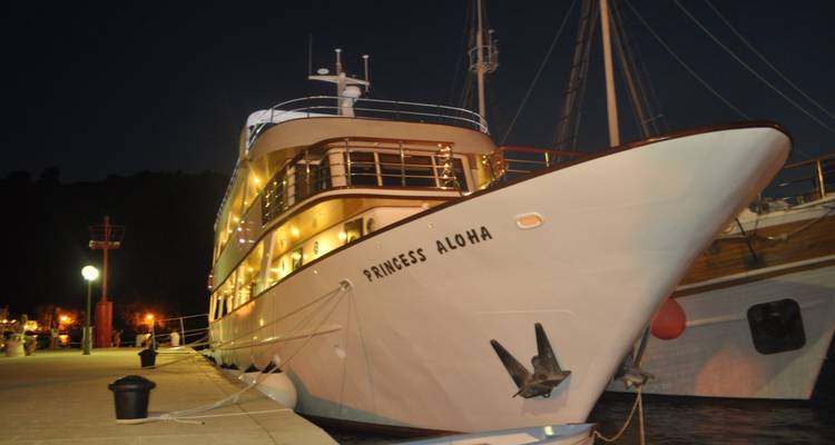 Kreuzfahrtschiff 'Princess Aloha' nachts am Kai vertäut, warm entlang des Kais beleuchtet.