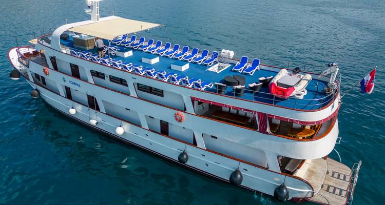 Oberdeck eines Kreuzfahrtschiffs mit blauen Sonnenliegen über dem Meer.