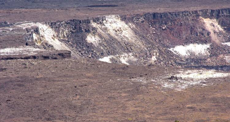 Barren volcanic crater rim with layered rock colors and sparse vegetation.