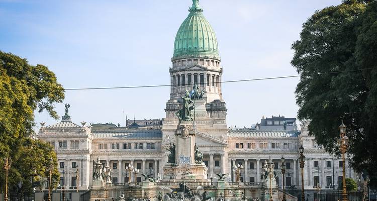 Grand facade of Argentina’s National Congress with verdigris dome framed by trees.