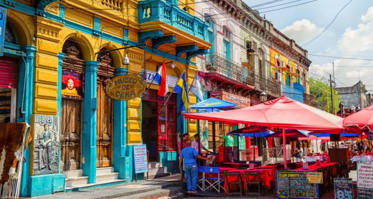 Colorful houses and open-air restaurants of La Boca’s Caminito with tourists strolling by.