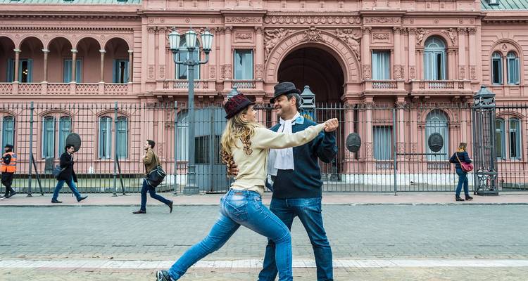 Couple dancing tango in front of the pink Casa Rosada palace in Buenos Aires.