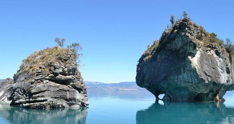 Two freestanding marble islands rise from glassy blue water against a clear sky.