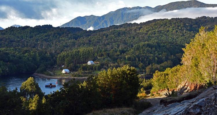 Forest-clad hills surround a tranquil inlet dotted with small cottages.