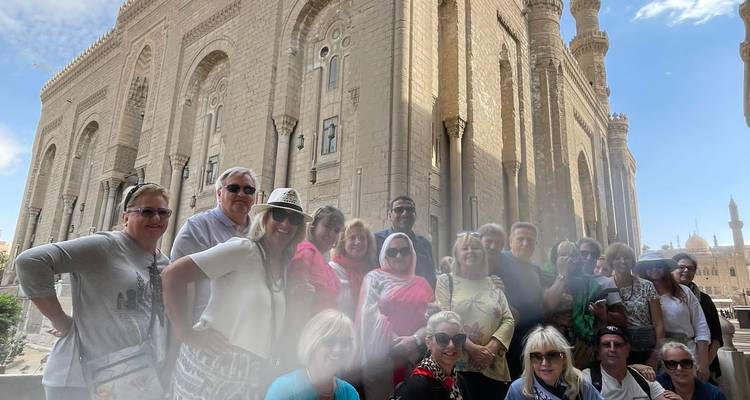 Photo de groupe de visite touristique devant une grande mosquée du Caire avec une légère brume au premier plan
