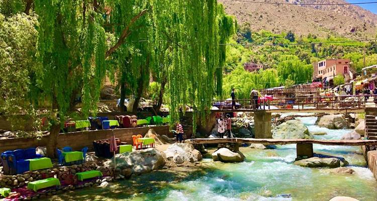 Les cafés au bord de la rivière aux chaises colorées bordent un torrent de montagne qui coule rapidement dans la verdoyante vallée de l'Ourika.
