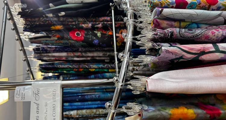 Rack filled with colorful patterned silk scarves and ties displayed in a shop.