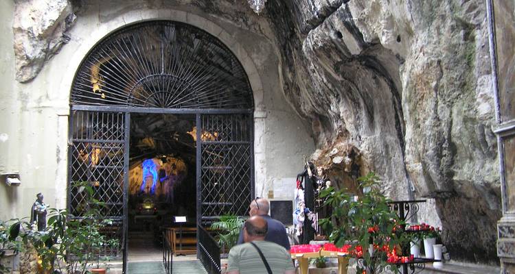 Les visiteurs entrent dans un sanctuaire creusé dans la roche par une porte en fer située dans une paroi de grotte spectaculaire.