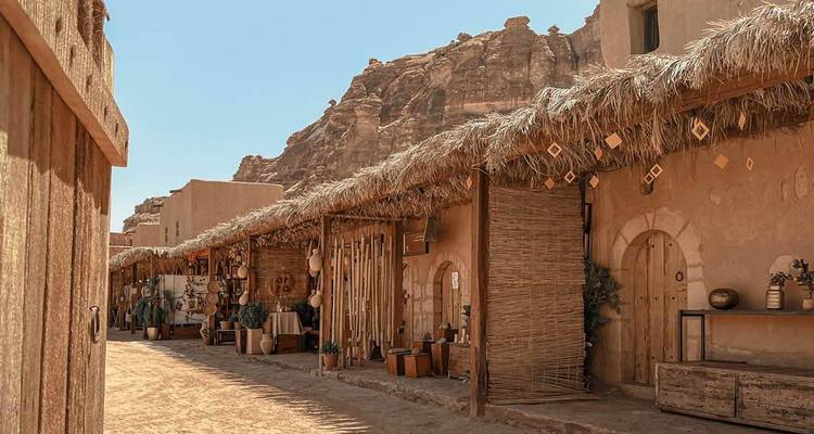 Rustieke marktstraat met aarden stalletjes en decoratieve palmendak-daken in de oude stad van Al-Ula.