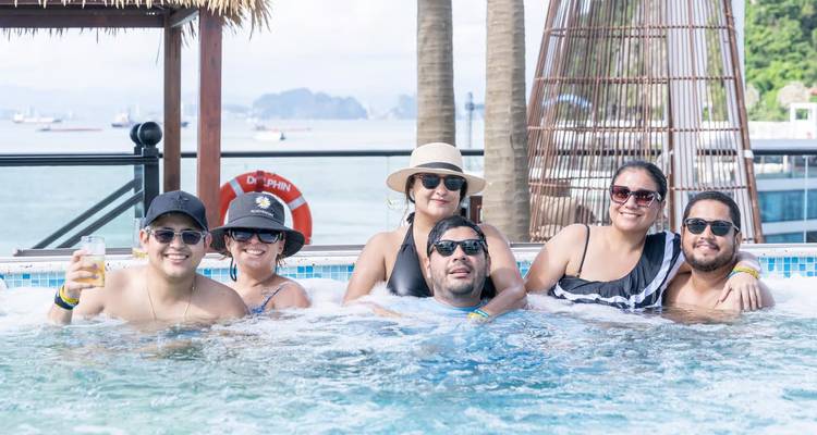 Friends enjoying jacuzzi on cruise deck with bay scenery behind.