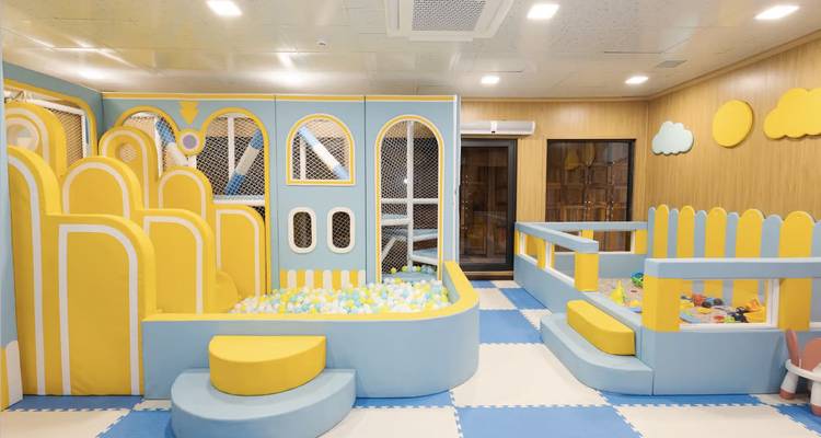 Empty indoor kids play area with soft mats, pastel fences and ball pit.