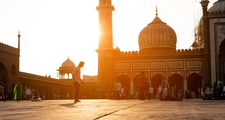 Gelovigen verzamelen zich in de binnenplaats van de Jama Masjid terwijl de zon achter de minaret ondergaat.