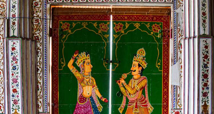 Levendige handgeschilderde tempeldeuren met Hindu-goden op een groene achtergrond.